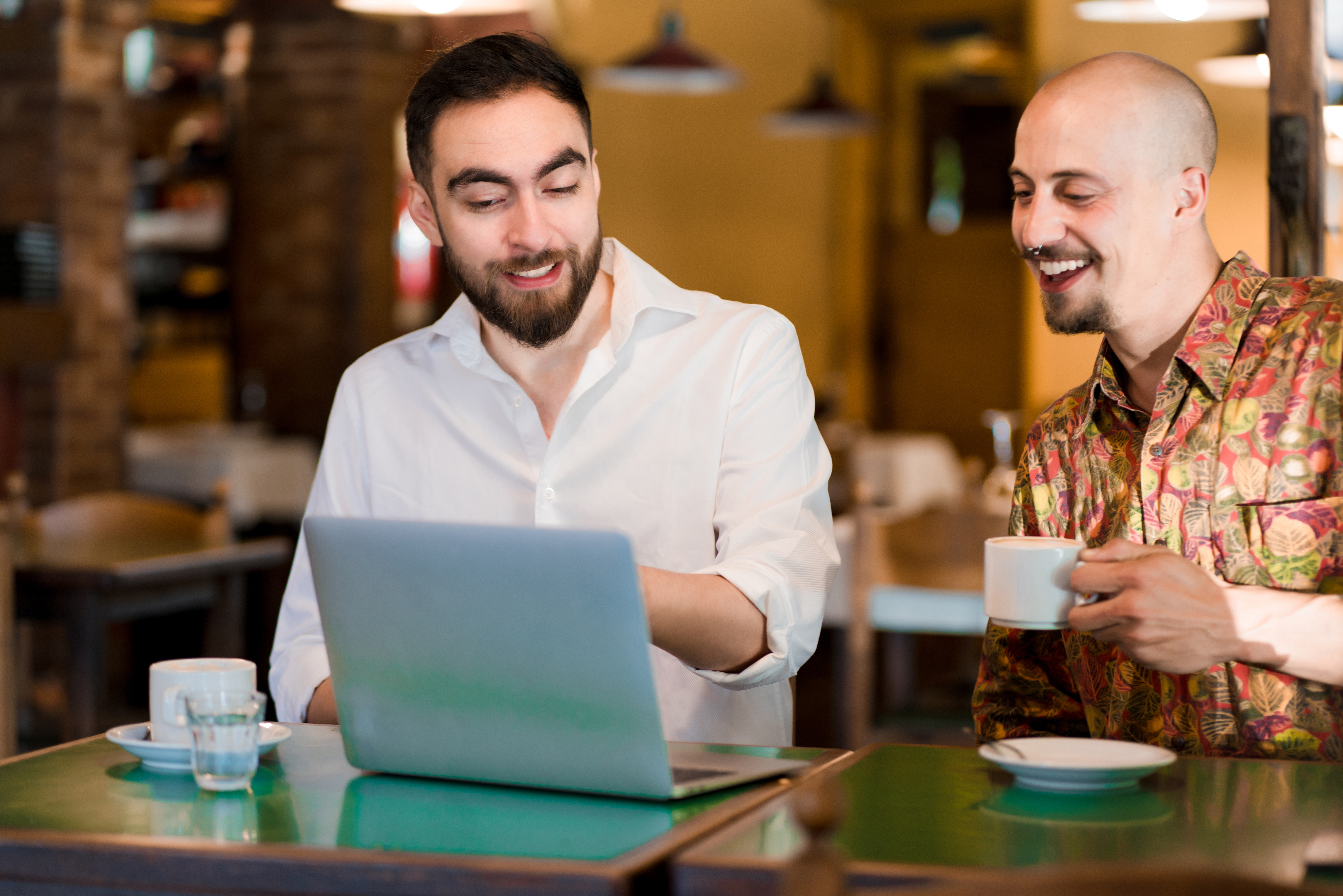 Two people going over figures on a laptop during a coffee shop meeting